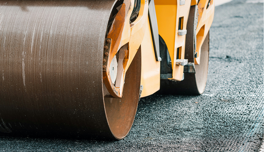 Browne Group - Close-up of road roller wheels compacting fresh asphalt on a road construction site.