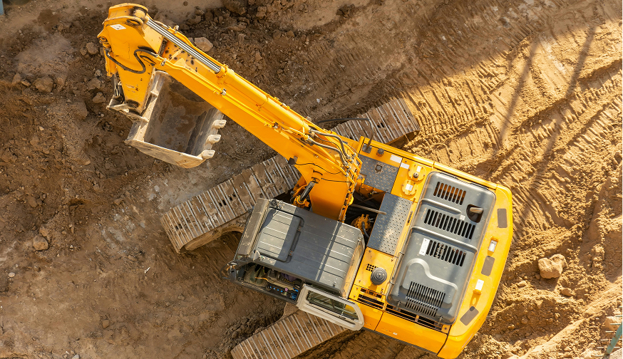 Browne Group - A yellow excavator digging in brown soil at a construction site, viewed from above.