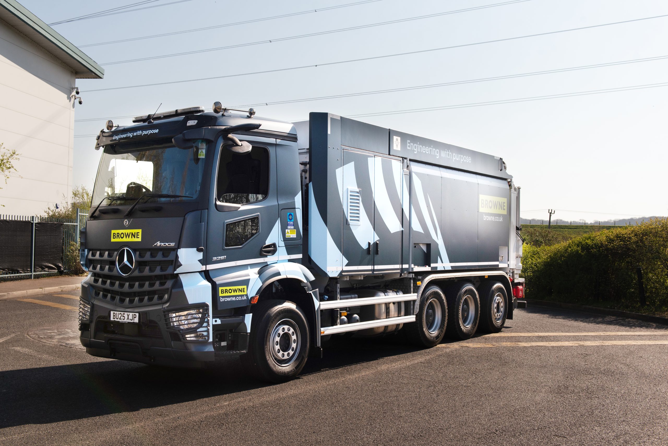Browne Group - A large blue Browne-branded Mercedes truck is parked on a road near a building and green shrubs.