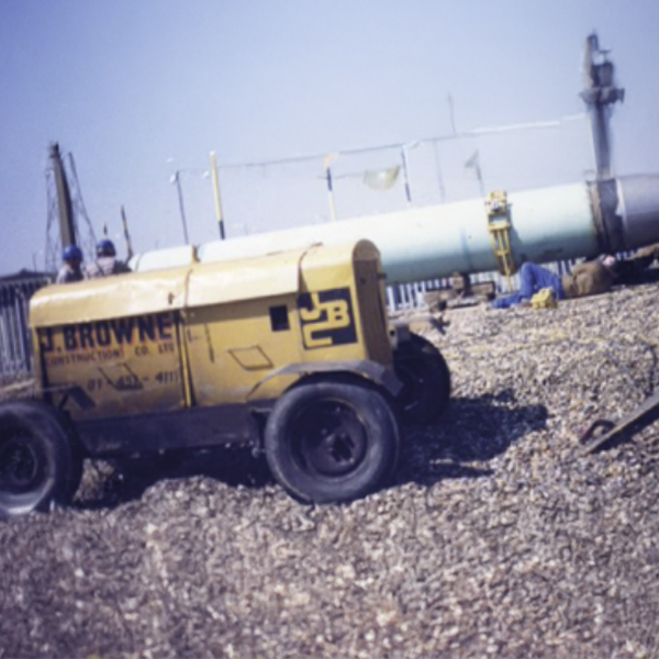 Browne Group - A yellow generator sits on rocky ground near a large blue and gray cannon at an outdoor site.