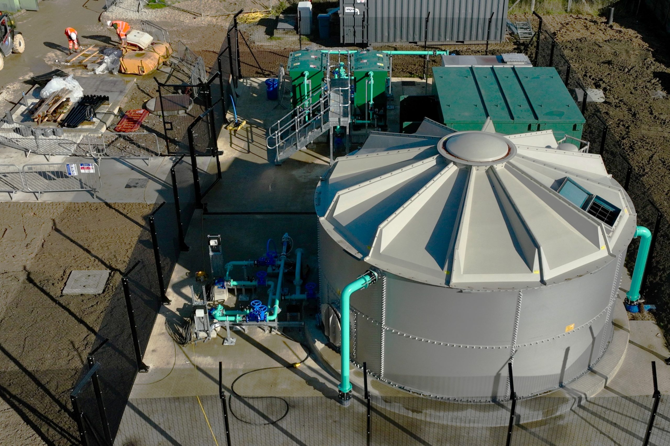 Browne Group - Aerial view of an industrial water treatment facility with tanks, pipes, and workers on site.