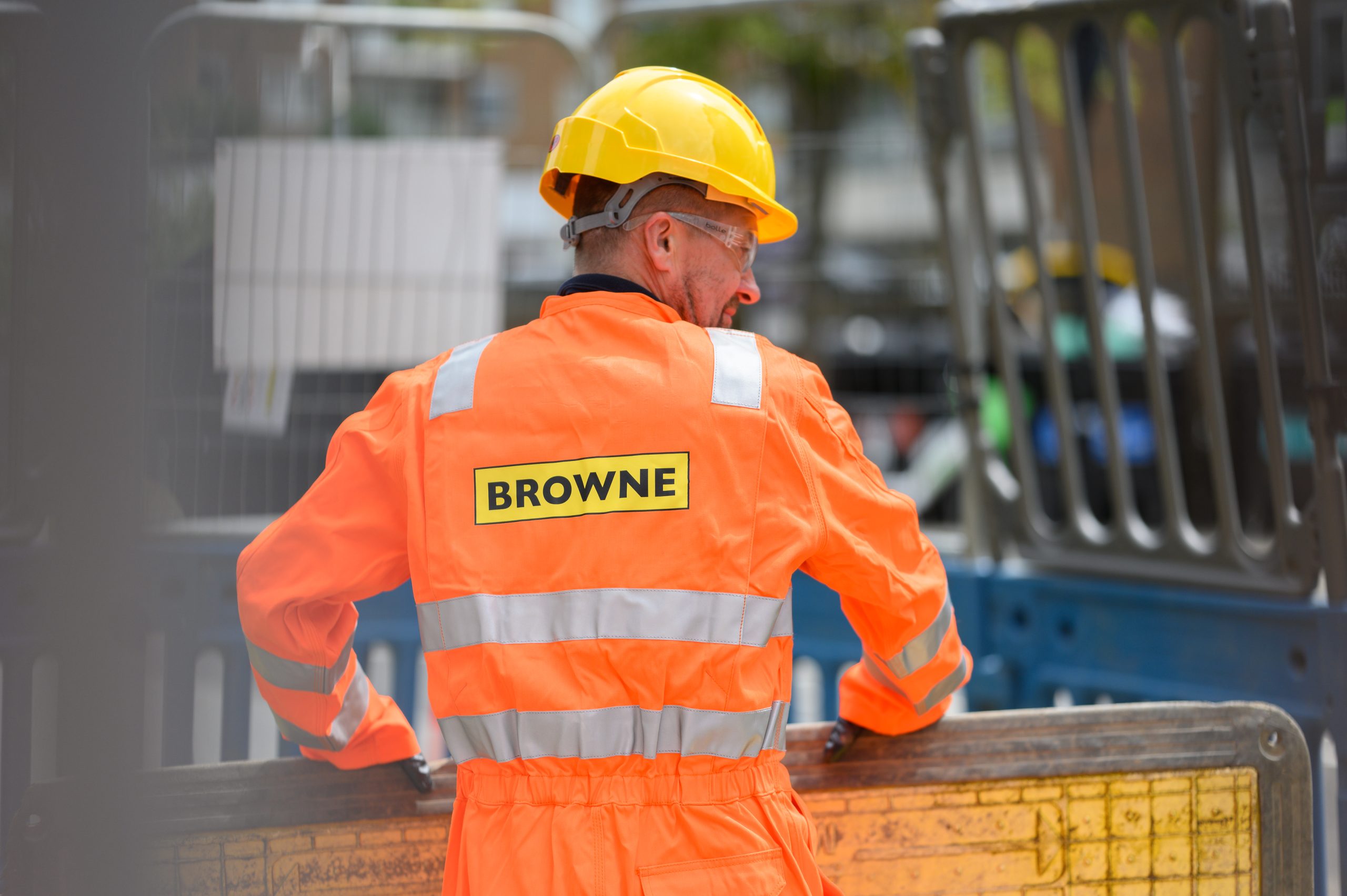 Browne Group - Construction worker in orange coveralls and yellow helmet, 