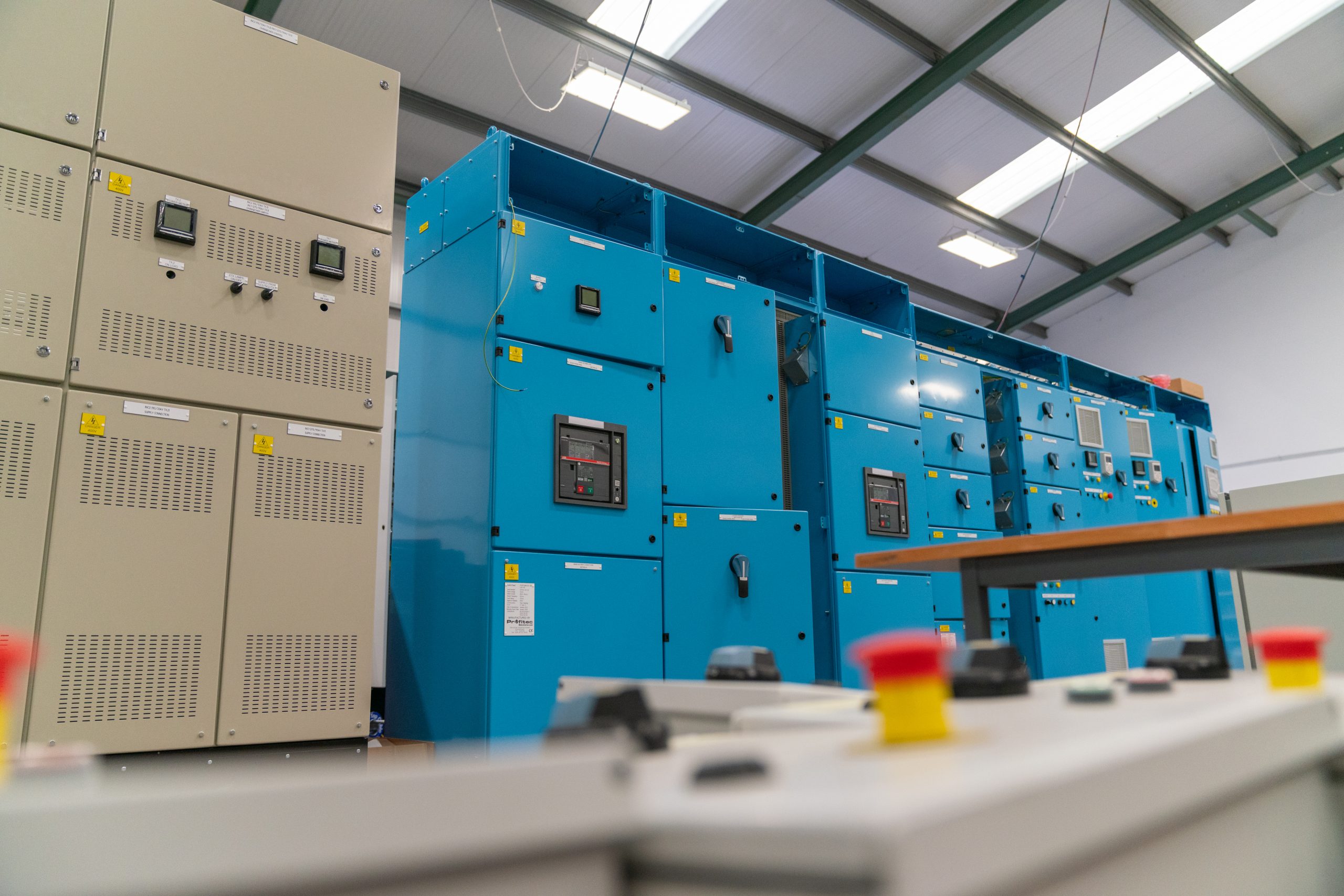 Browne Group - Industrial control panels and blue electrical cabinets in a large, well-lit facility with emergency stop buttons.
