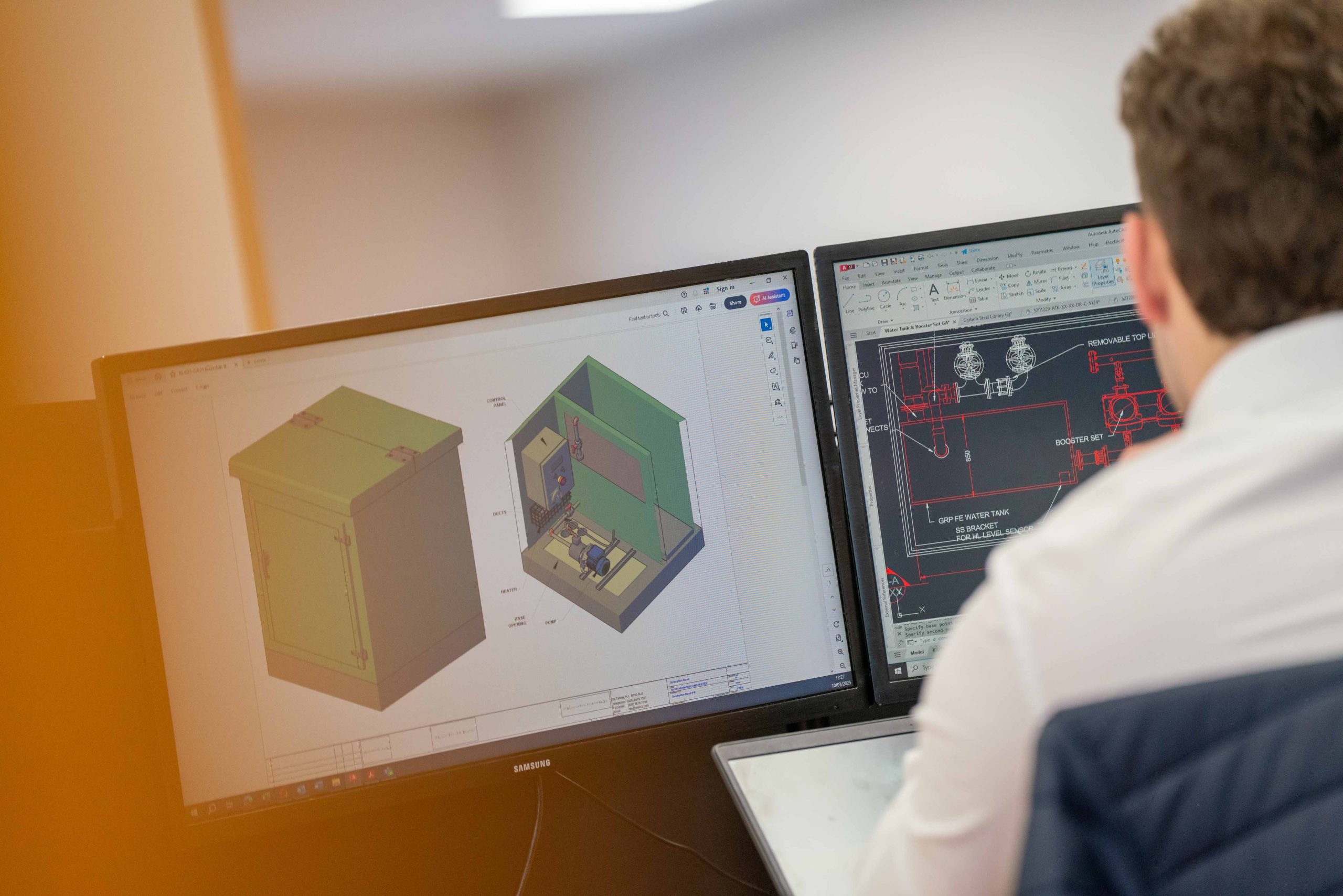 Browne Group - A person works at a desk with two monitors displaying 3D and technical engineering designs.