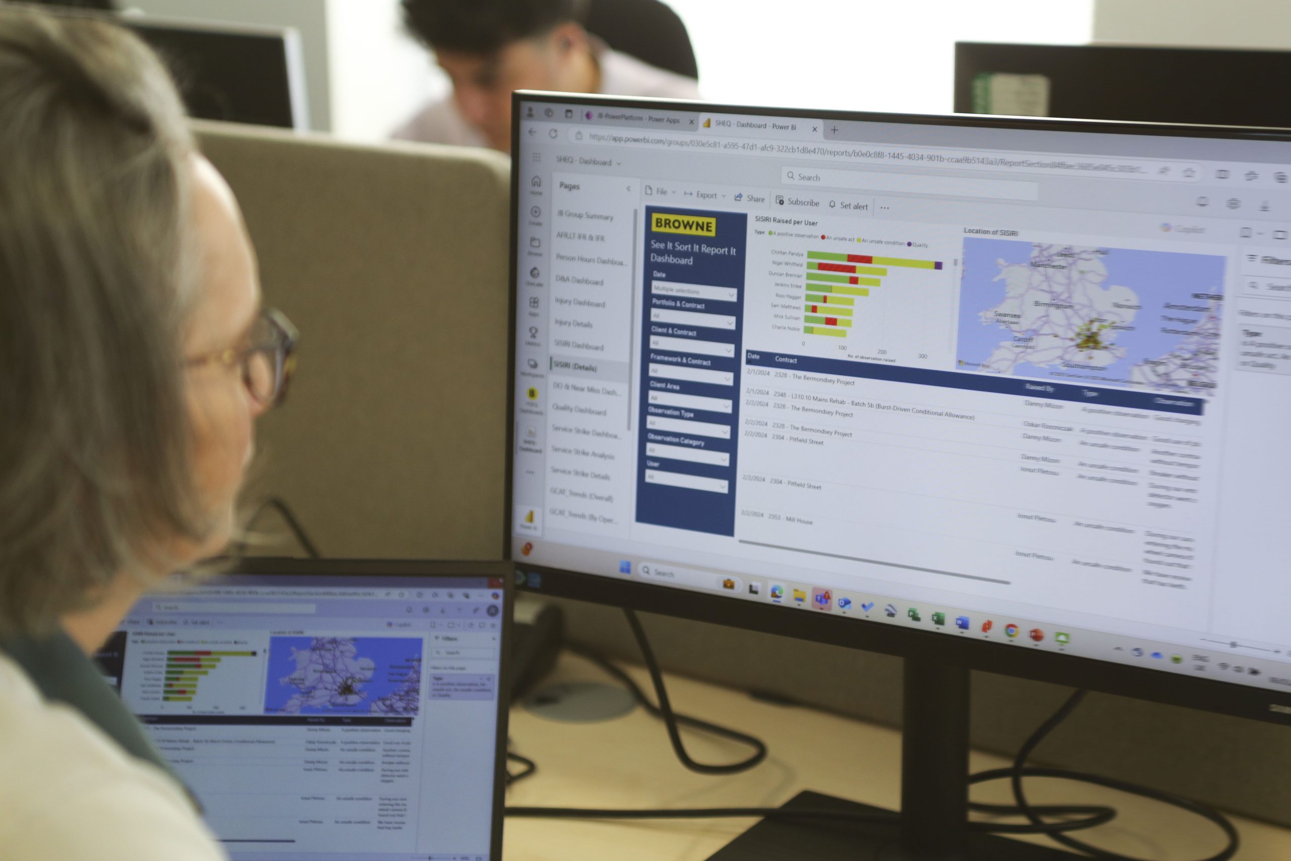 Browne Group - Person at desk viewing data charts and a map on a computer monitor, with a laptop displaying similar content.