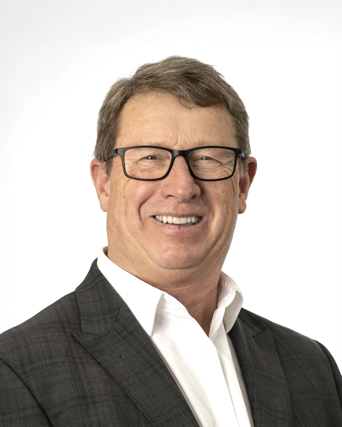 Browne Group - Smiling man with glasses in a business suit and white shirt on a plain white background.
