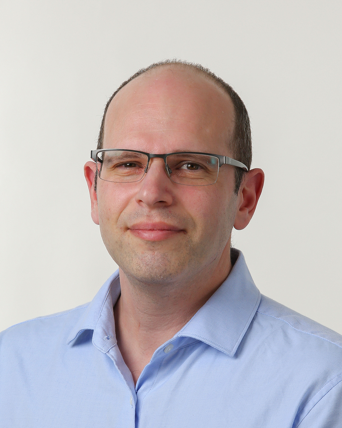 Browne Group - Man wearing glasses and a light blue shirt, posing against a plain white background.